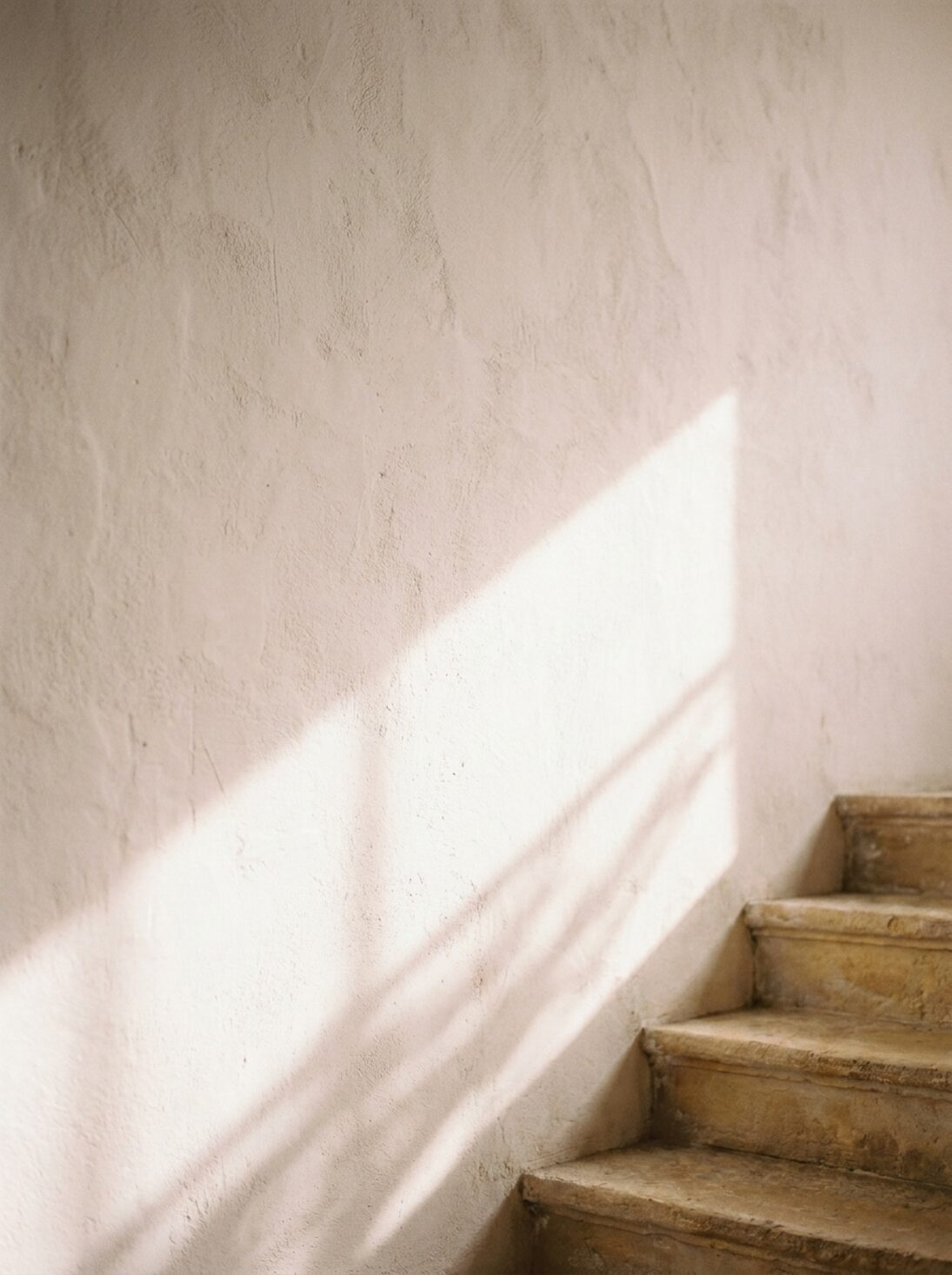 Light climbing a wall beside stone stairs